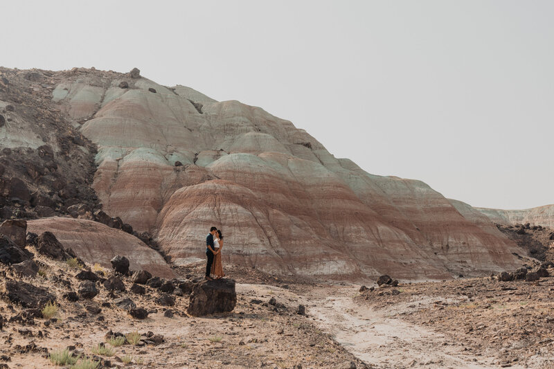 A couple stands in front of blue hills outside of Moab Utah