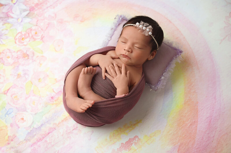 baby photography session aith baby posing on rainbow backdrop.
