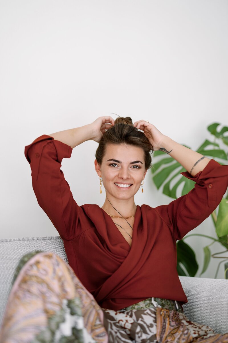 smiling woman tying hair on couch