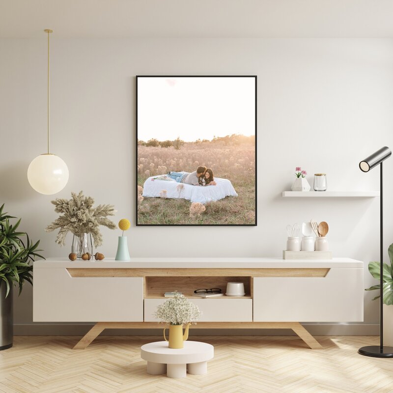 Artwork mockup of a living room with a canvas of a couple laying in a field at sunset during couples photos