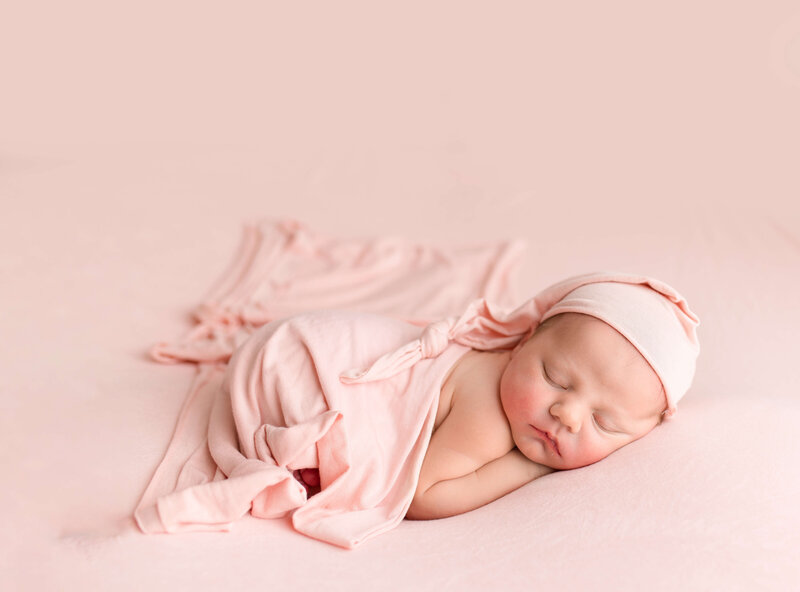 Girl on pink fabric wearing sleepy cap
