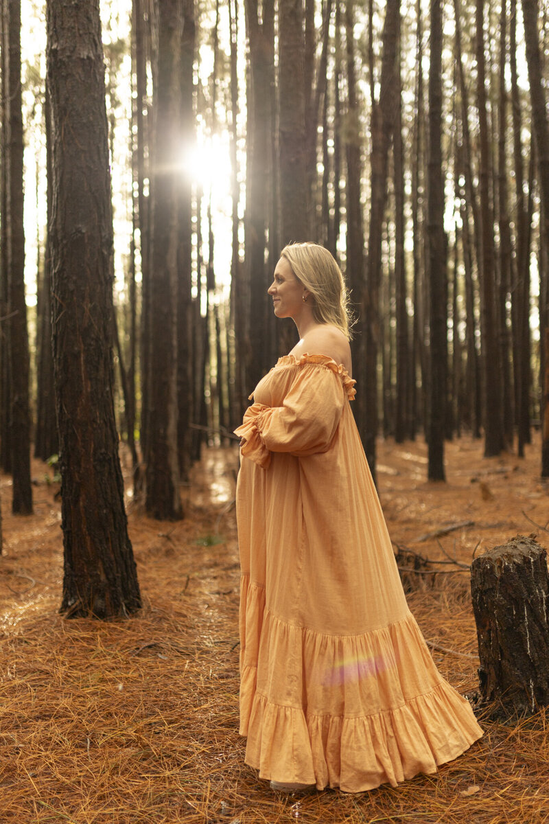 Pregnant lady sitting on sand with orange dress on