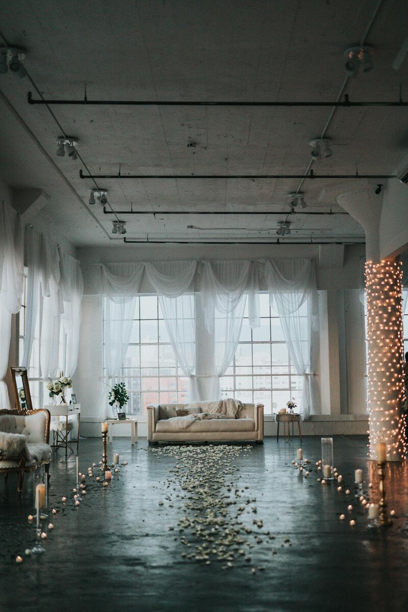 Urban indoor wedding ceremony space in Portland, Oregon wtih flower petals and candles illuminating the industrial space 