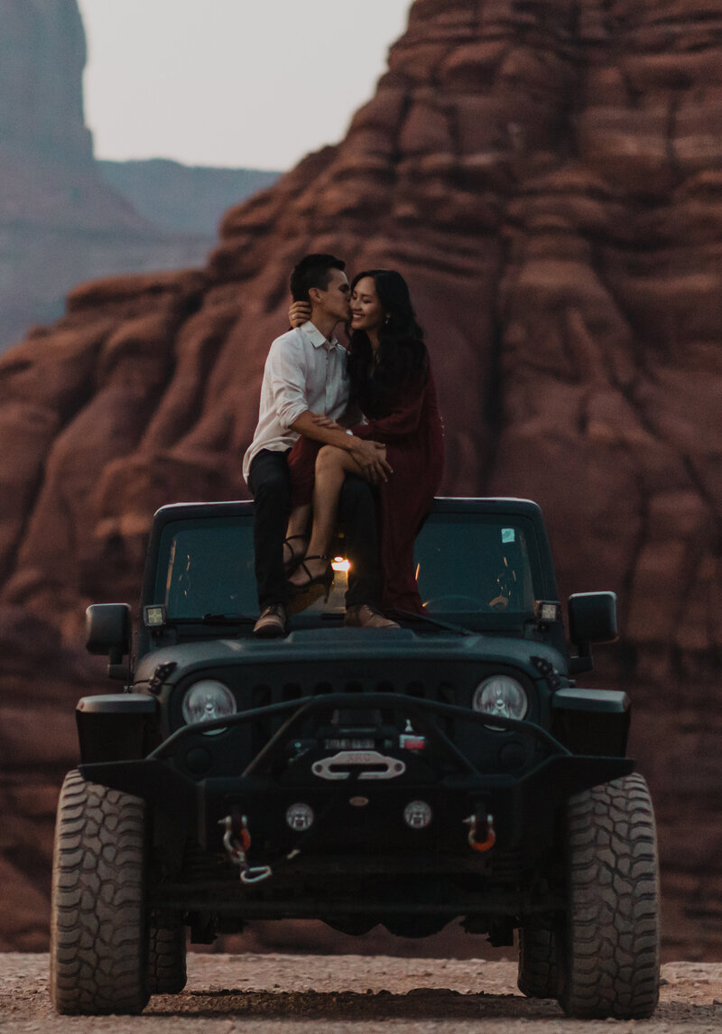 Couple sits on their Jeep during an offroad engagement session in Moab Utah