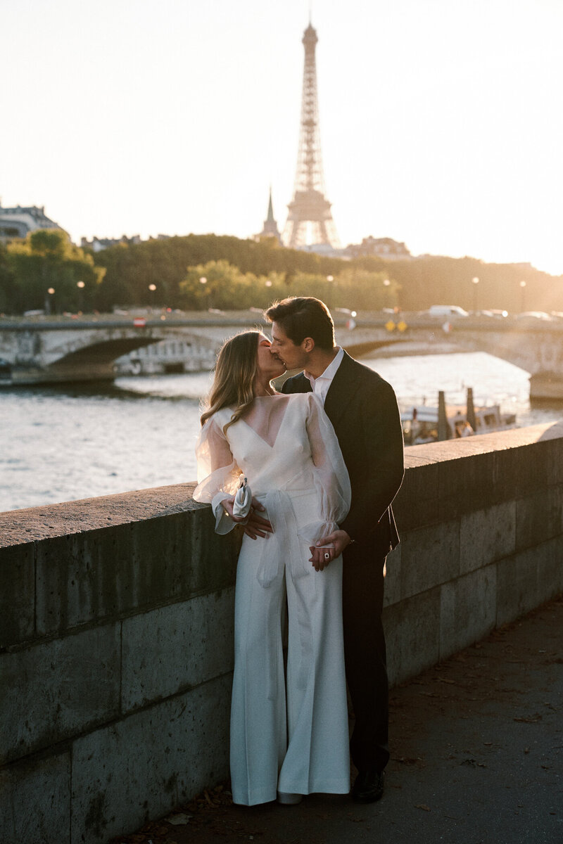 Bride and groom kissing by river