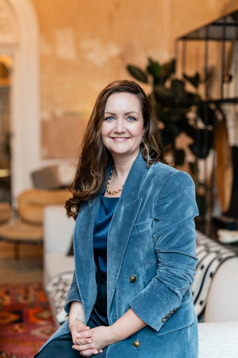 Bryony Williams in blue blazer sitting on a soffa