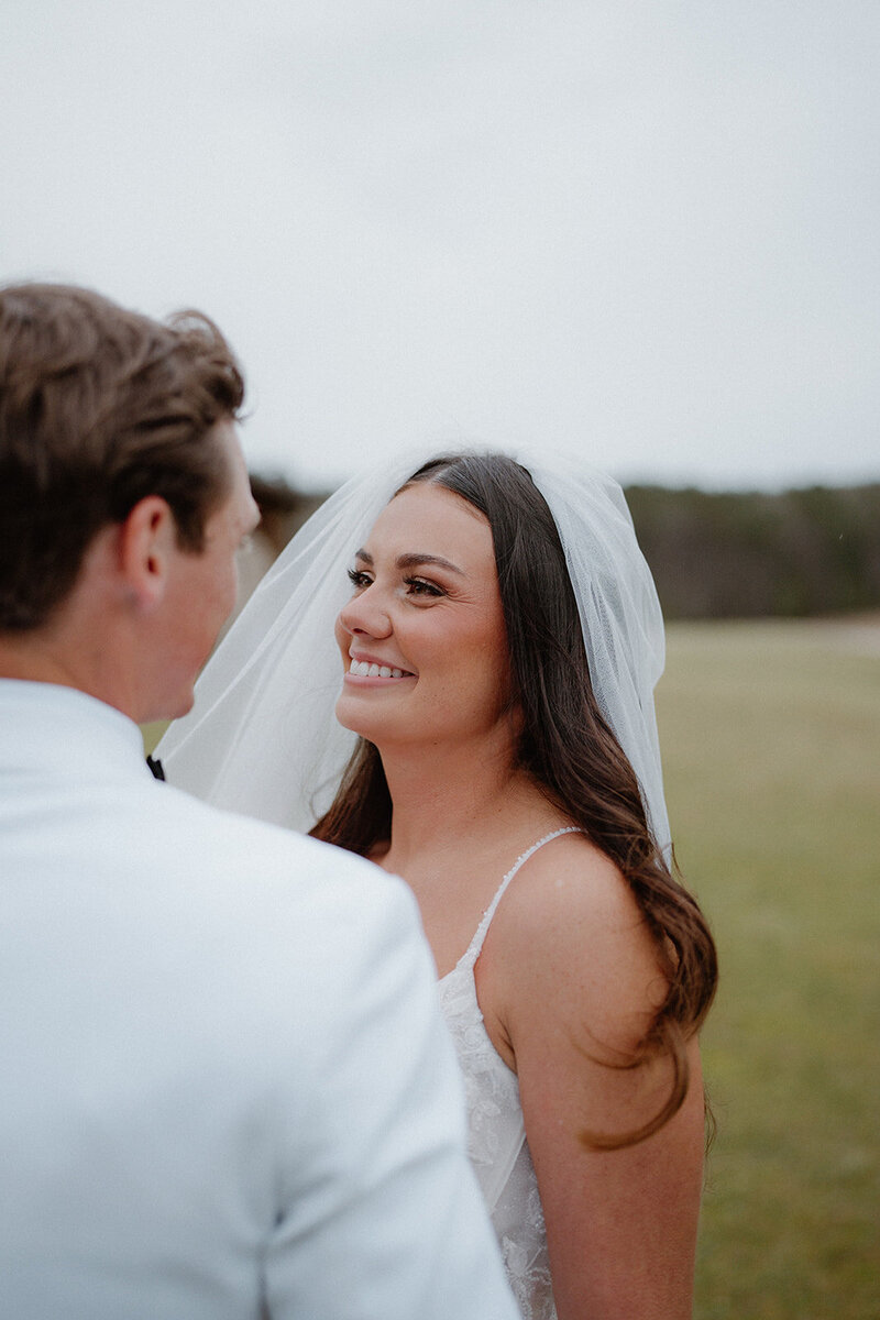 photo of bride and groom in a field looking longingly into each others' eyes