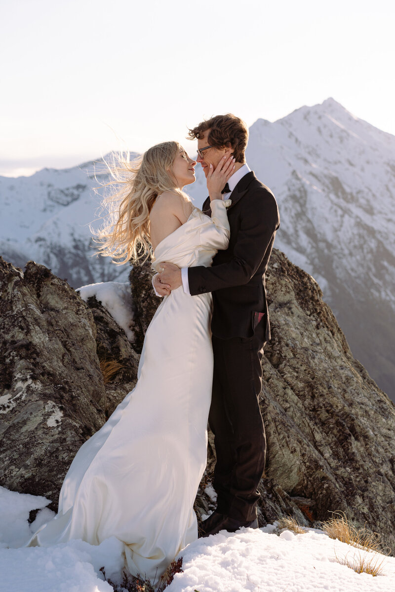 bride and groom stand on  mount crichton a snow capped mountain for their intimate elopement wedding