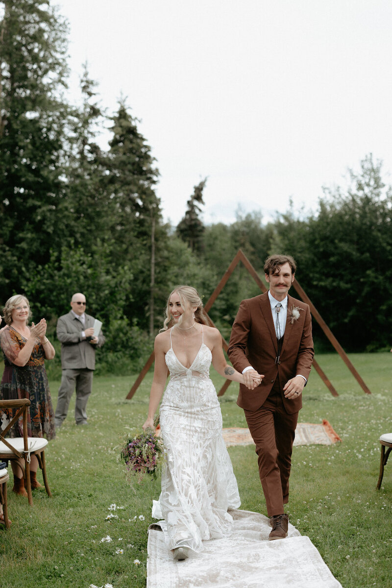Couple walking away together while holding hands.
