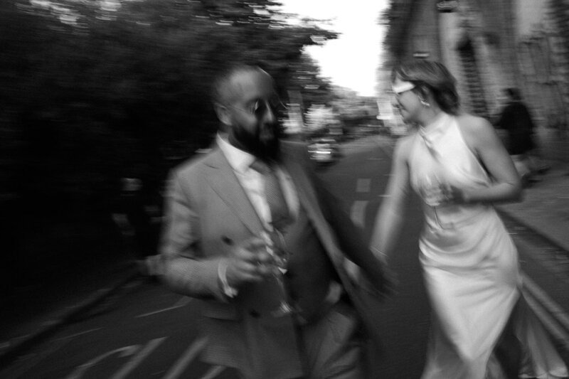 A wedding couple blow pink and red confetti at the camera.
