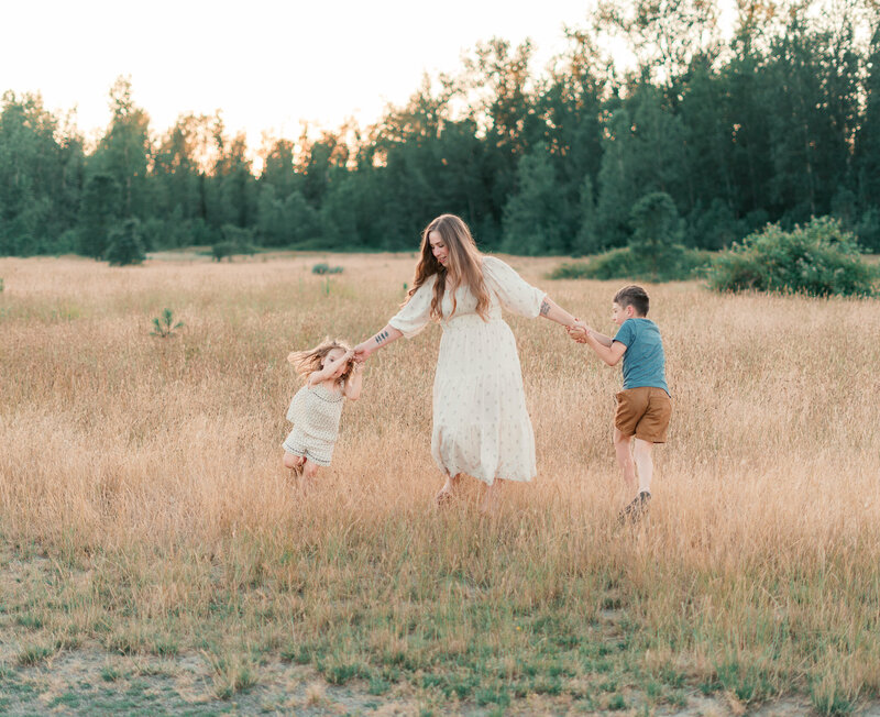 A mother dancing with her two children in a field in portland