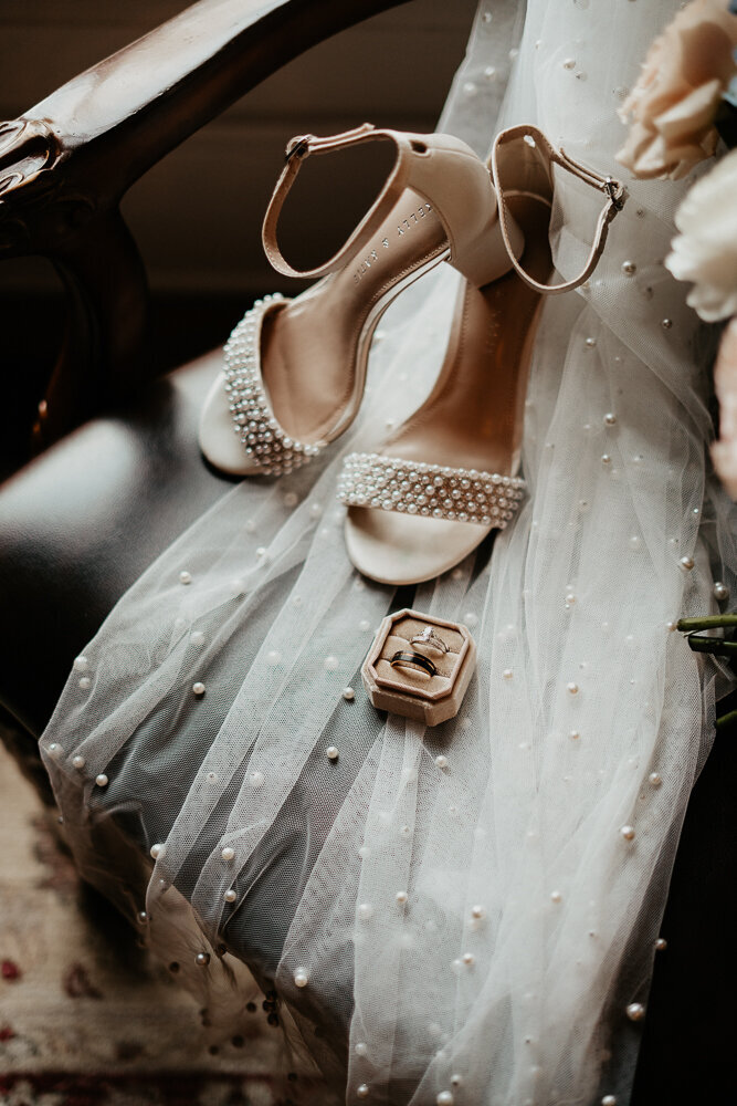 Flatlay of wedding shoes and rings with veil