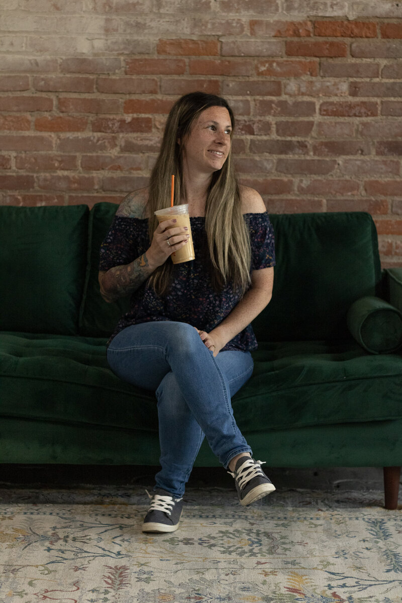 alison altrui of christella photogrphy holding a dunkin donuts coffee and looking towards the window smiling