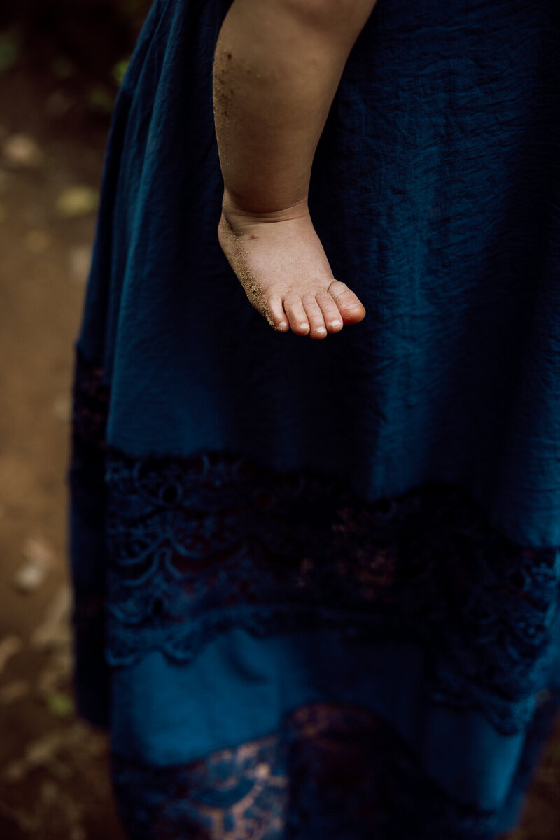 An in between moment taken during a family portrait session of a child's foot while being carried by her mother. 