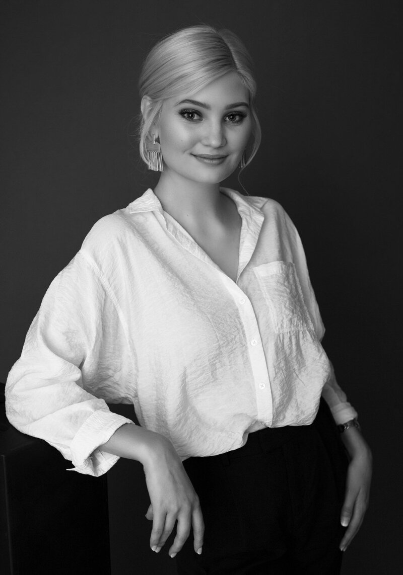 A young woman with platinum blonde hair styled in a sleek updo, wearing a crisp white shirt. 