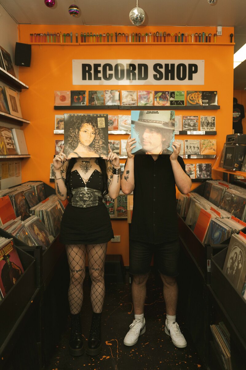A couple holding up retro records from a record shop in Cardiff, Newcastle, NSW. Authentic, cinematic  photography available anywhere in Australia.