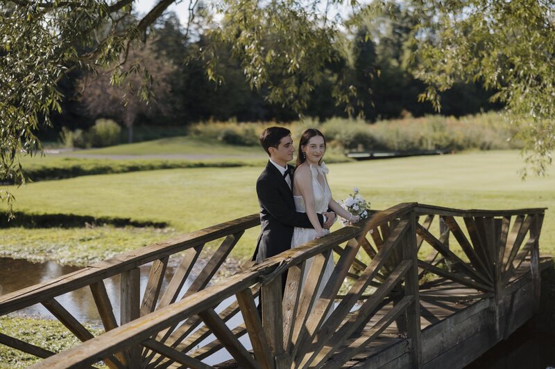 bride and groom posing on a bridge