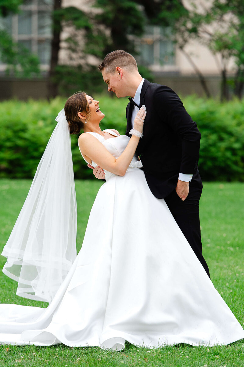 a groom in a black suit dipping his laughing bride outside the Chateau Laurier wedding venue.  Captured by Ottawa wedding photographer JEMMAN Photography