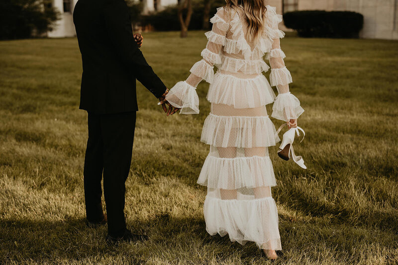 bride and groom holding hands walking through a field