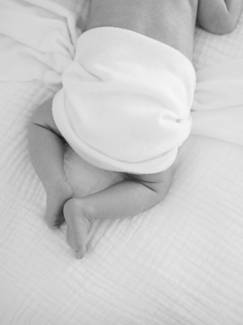 A close-up of the back of a baby wrapped in a white blanket at a newborn photography session in Richmond by Katie Stansfield Photography.