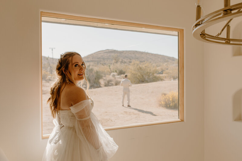 Bride smiling at camera in front of window