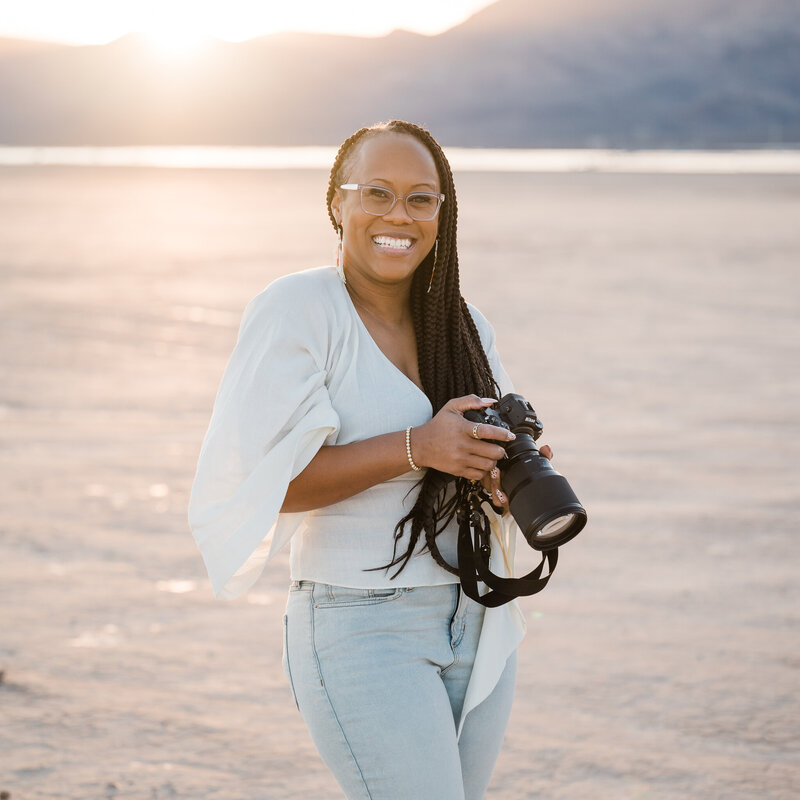 Black female  wedding photographer holding camera in desert