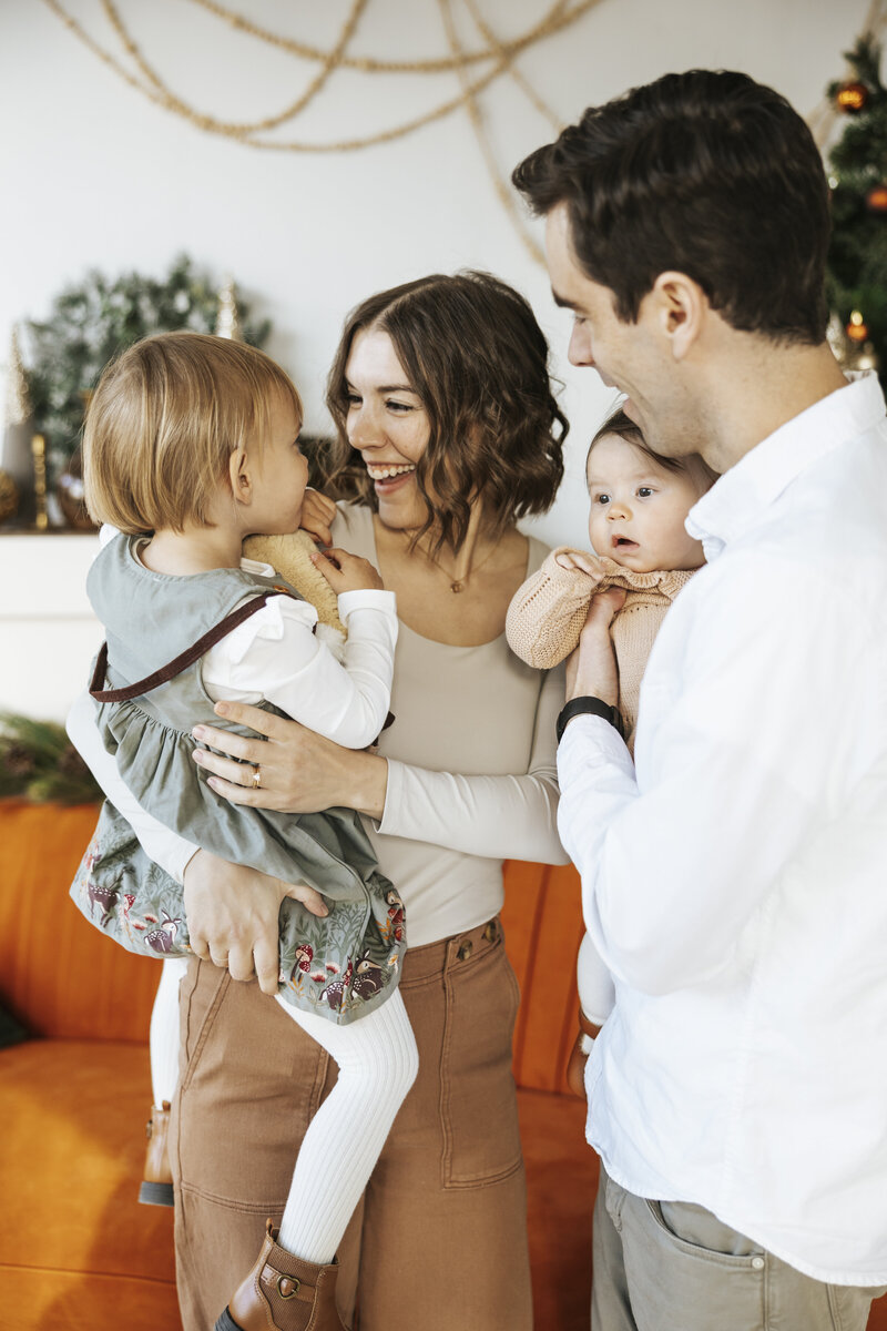 A family of five standing together smiling in a wooded area.