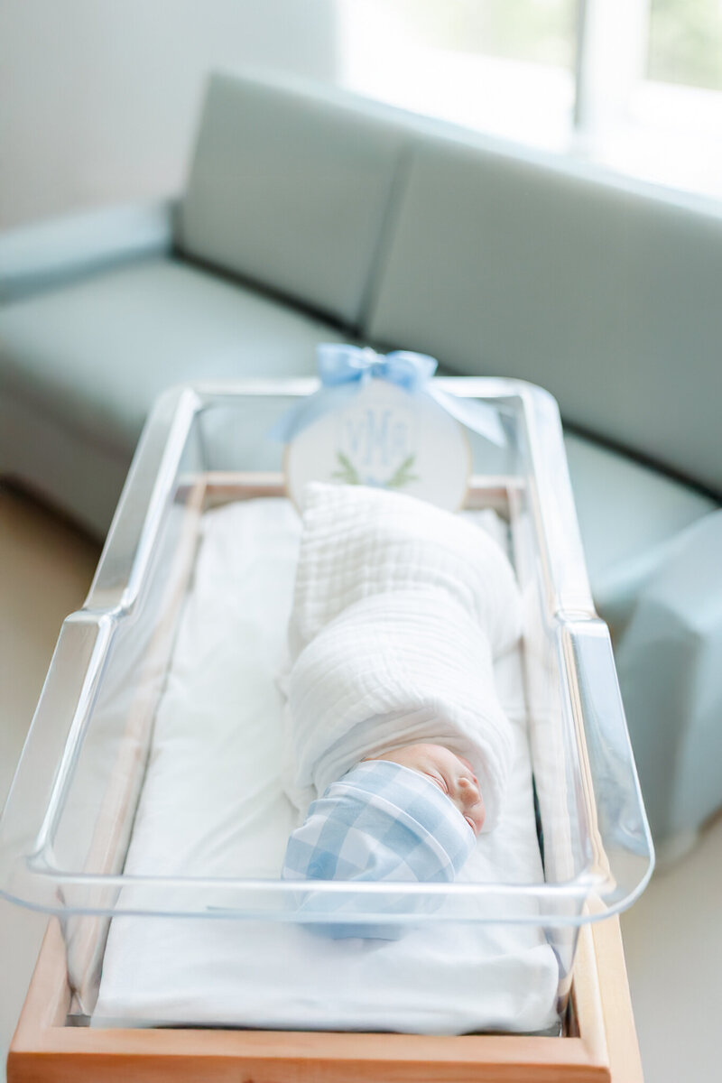 newborn baby boy laying in hospital crib swaddled in white blanket during fresh-48 session at Grandview medical center in Birmingham, AL with 5U Photography