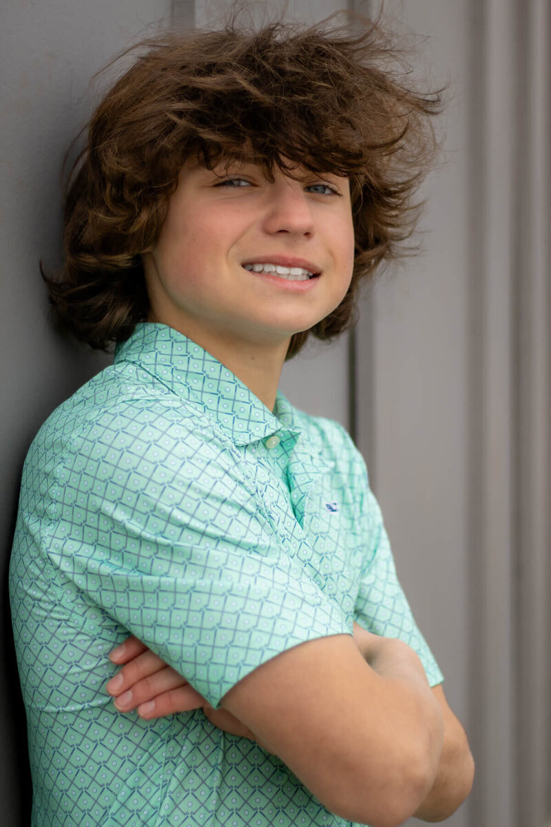 teenager leans against wall during his family photo session