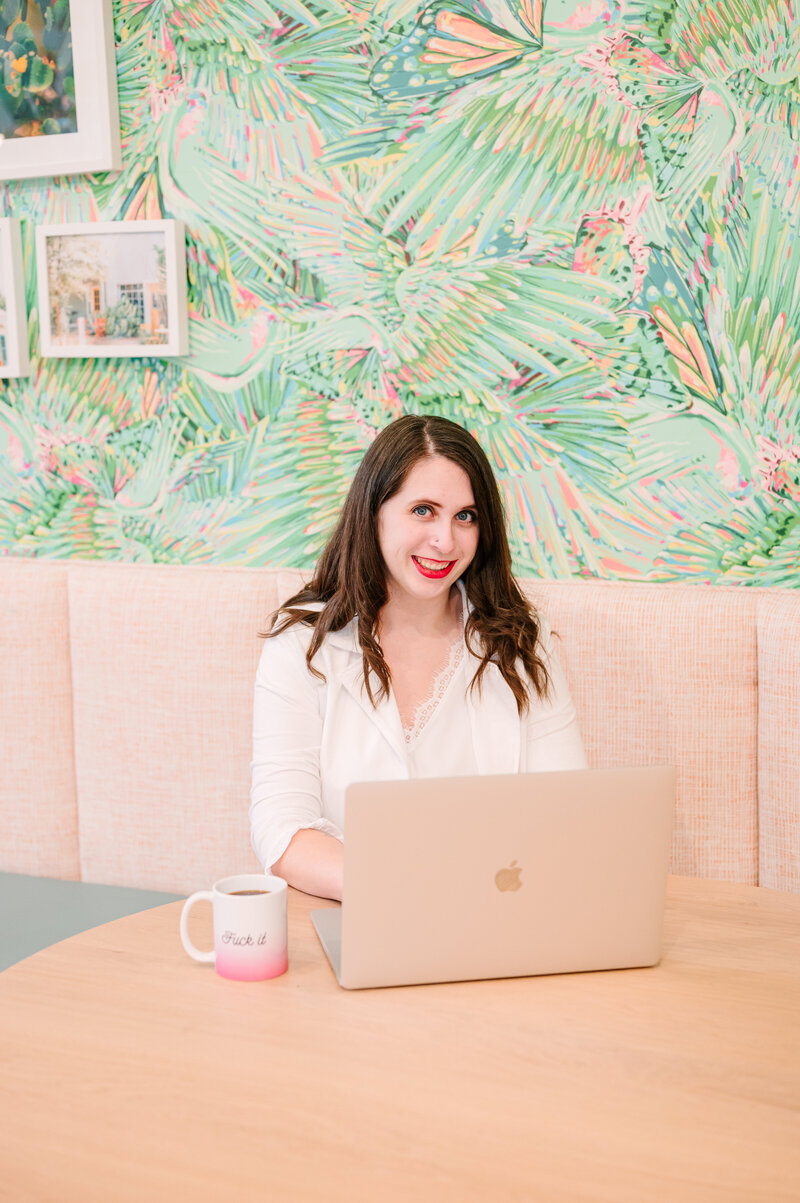Cait Potter at a laptop in front of palm-print wallpaper