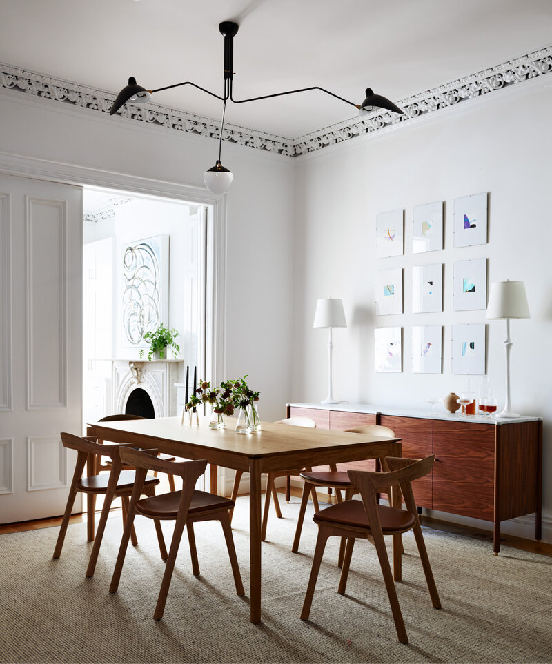 Brownstone Interior Designers in Boston designed a modern dining room with a Bok dining table, walnut sideboard, and black mid-century modern light fixture.