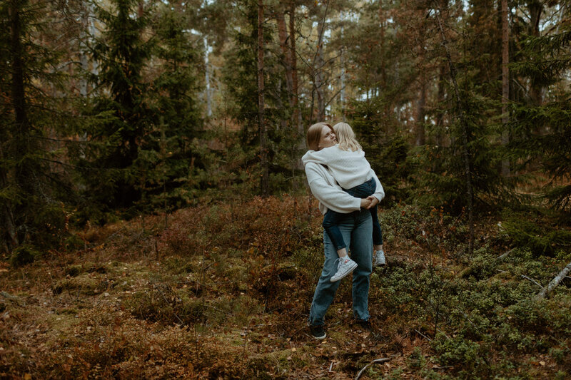 Äiti pitelee sylissä lastaan metsän keskellä syksyllä Kallahdessa Helsingissä