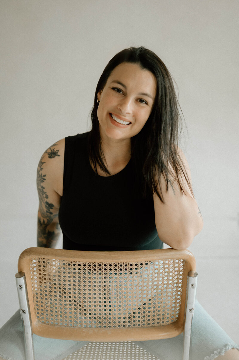 Brunette woman sitting on chiar smiling at camera