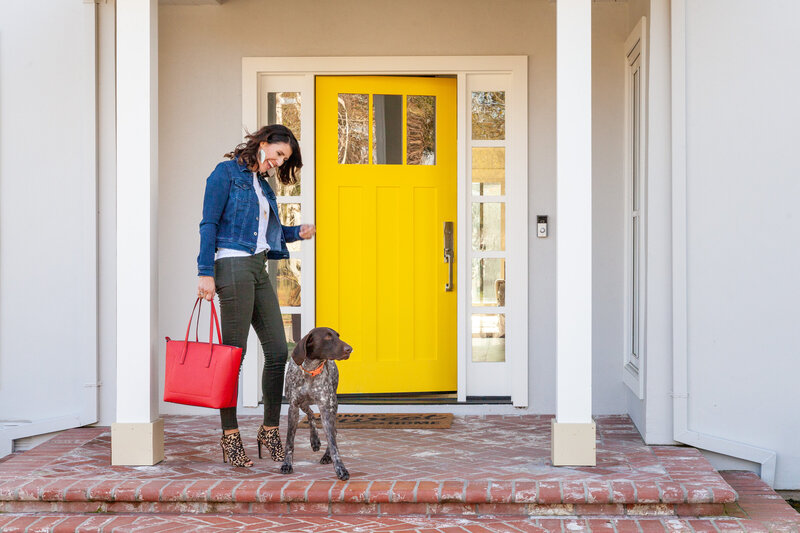 Interior design photography of a woman and dog at a front door with a yellow accent.