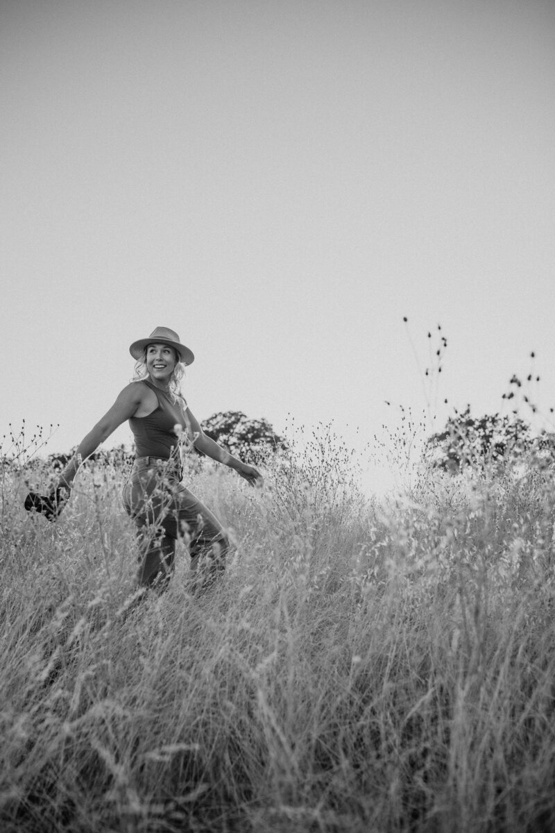black and white of sacramento Wedding photographer posing with camera in field