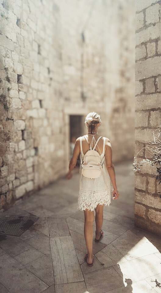 Tourist walks down stone street in Old Town Dubrovnik, Croatia searching for Cafe Buza.