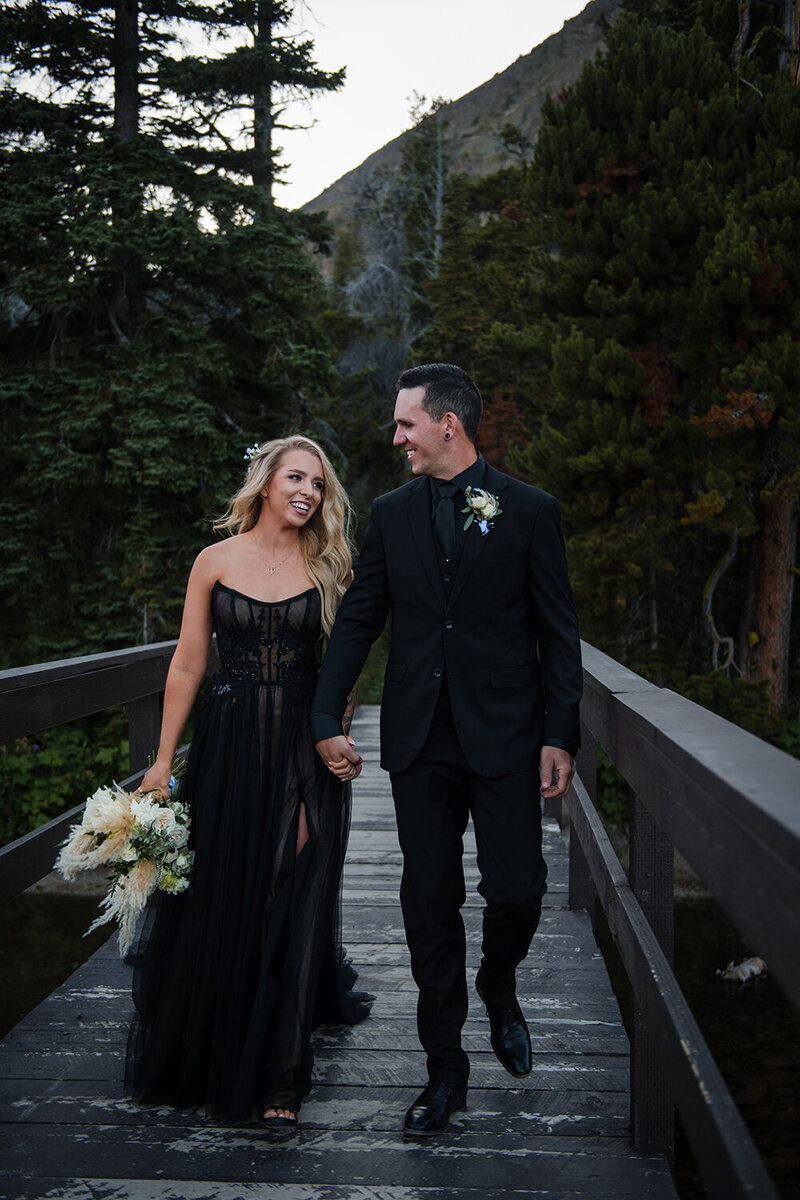 A bride and groom walk hand in hand through Glacier National Park in western Montana.