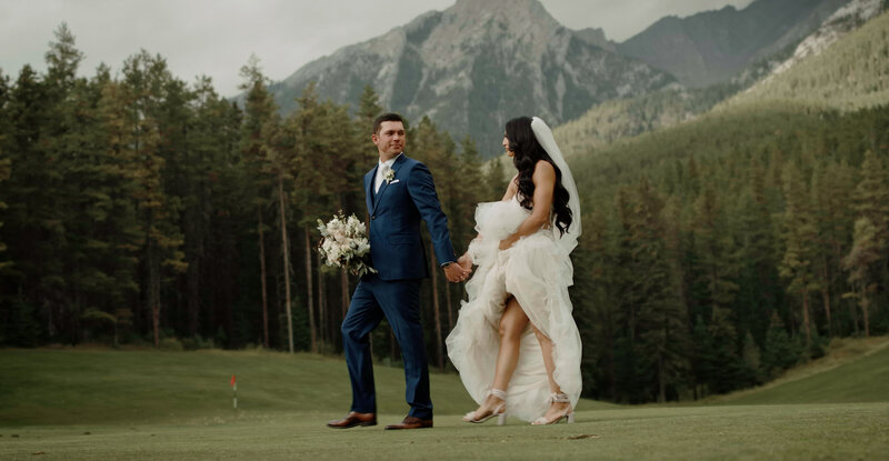 Couple walking across a field in Canmore AB on their wedding day at silvertip resort