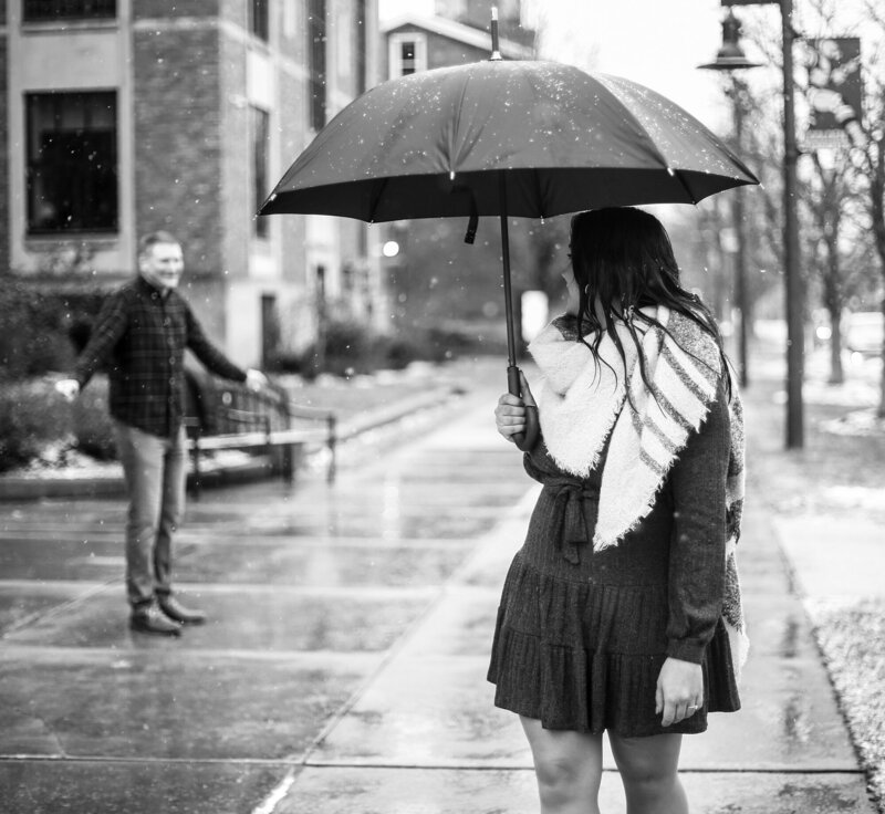 Woman standing under umbrella looks back at fiance in downtown Erie PA