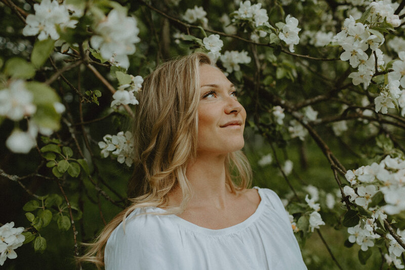 Portrait of a woman looking up and smiling with apple blossoms in Helsinki in Finland