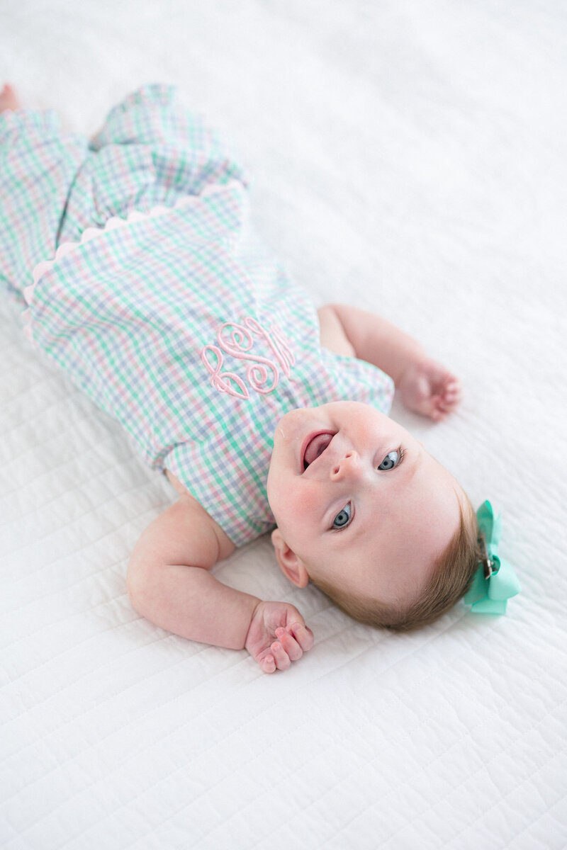 Newborn baby girl swaddled in a Beaufort Bonnett bow swaddle in a white crib
