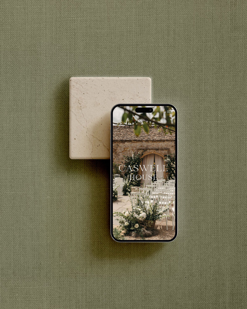 Phone mockup of the Caswell House website placed on green linen fabric