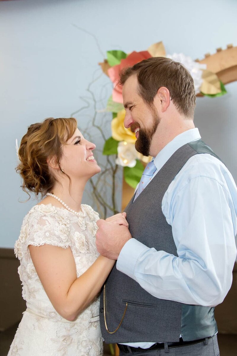 a bride and groom look at each other during their first dance