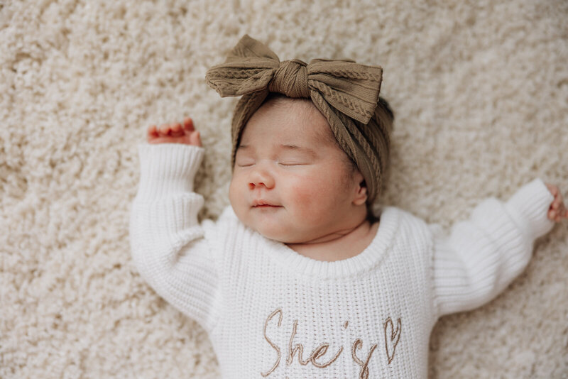 A close up portrait of a newborn girl smiling and showing her dimple