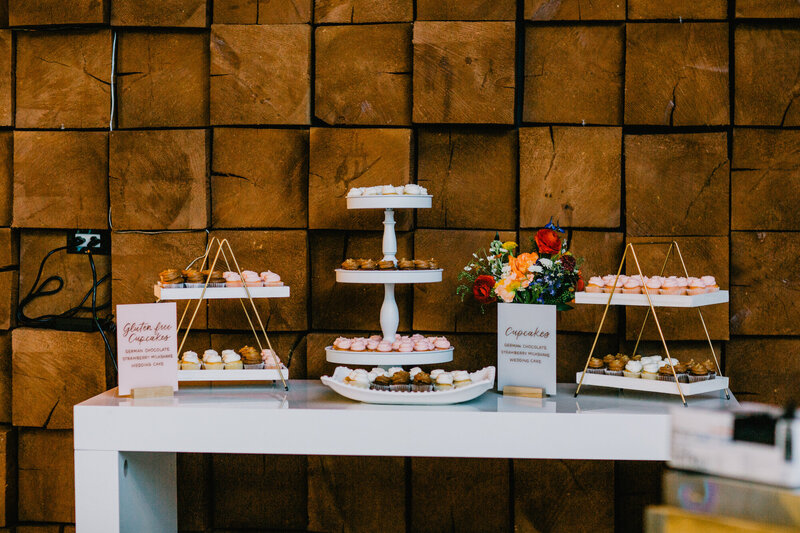 Dessert station with calligraphy signage for cupcake flavors