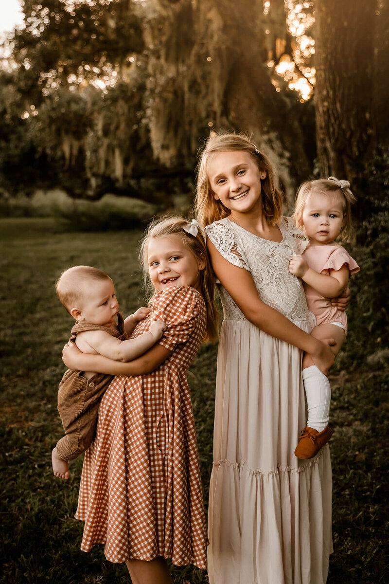 Kids holding siblings under a tree