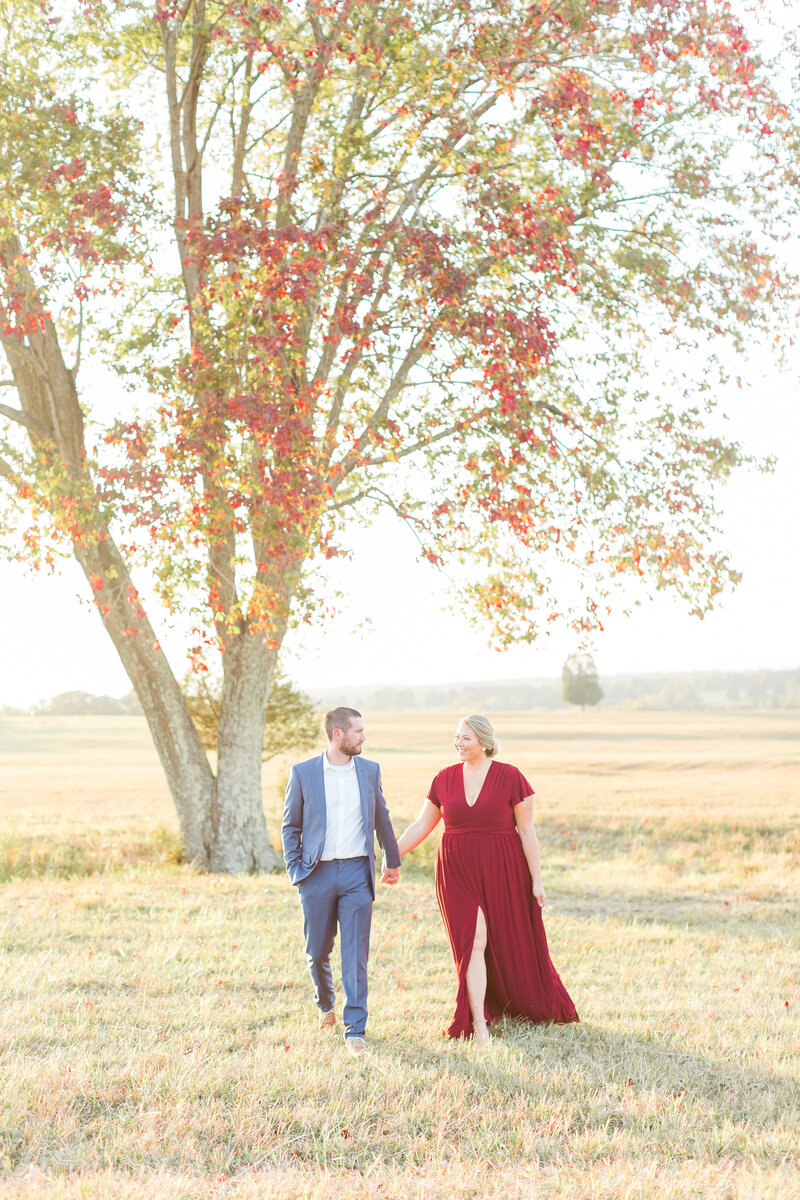 An expecting couple walking outside in the Fall for their Northern Virginia Newborn Photography photos