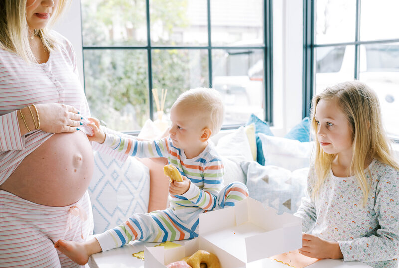 Mom and her children are having a donut party while wearing their PJ''s for an in home maternity session with Allison Krogness Photography