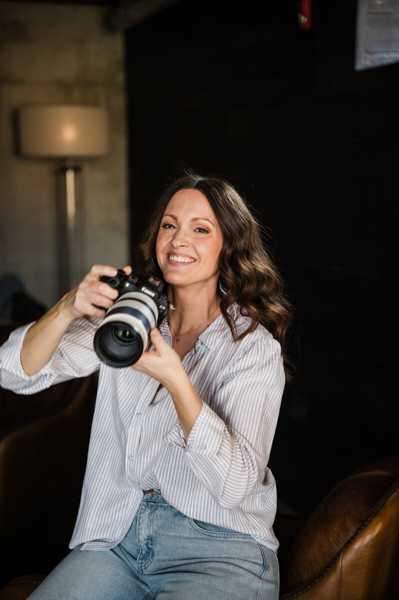 Woman smiling while holding a dslr camera, participating in a photography mentorship program.