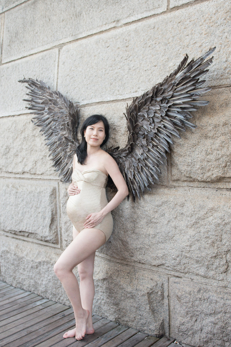 glamorous pregnant mom in bodysuit and wings